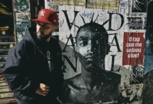 Rashid durante divulgação do álbum CUMULONIMBUS, com foto ao lado de mural de Sabotage