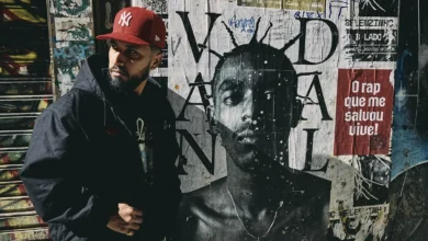 Rashid durante divulgação do álbum CUMULONIMBUS, com foto ao lado de mural de Sabotage